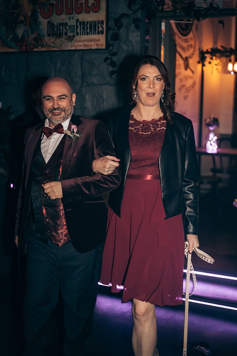 A stylish couple wields glowing lightsabers in a dimly lit urban setting.