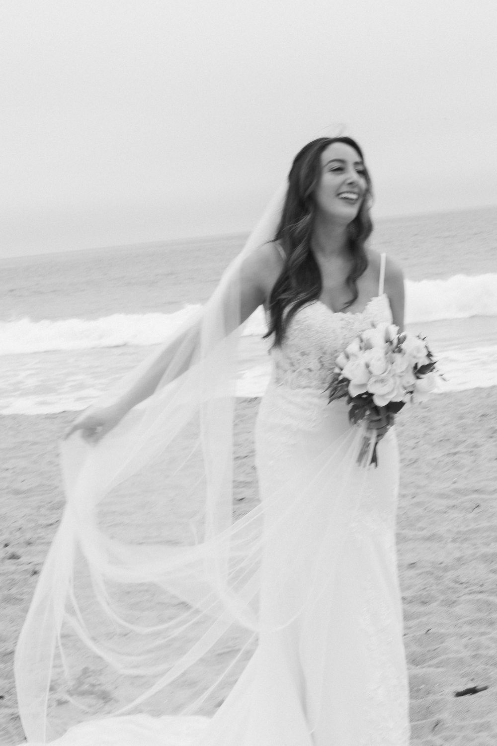 Candid film photo of the bride laughing and twirling her dress on the Malibu shore.