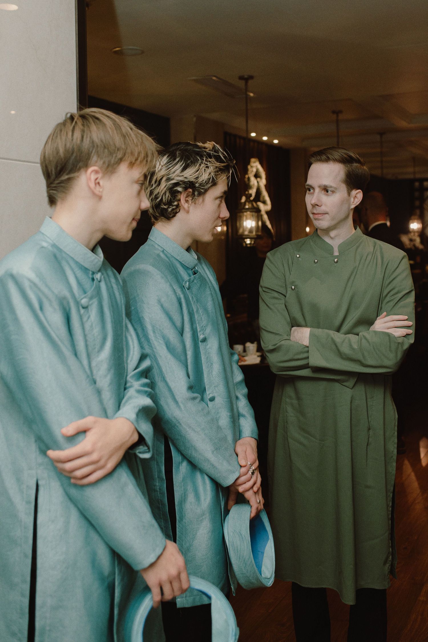 A group wearing matching light blue and green formal attire stands together in an indoor setting.