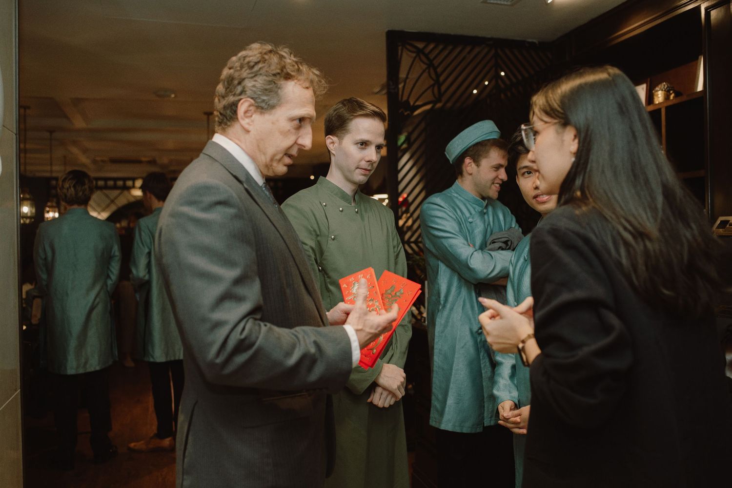 People gather at an indoor event exchanging gifts and engaging in conversation.