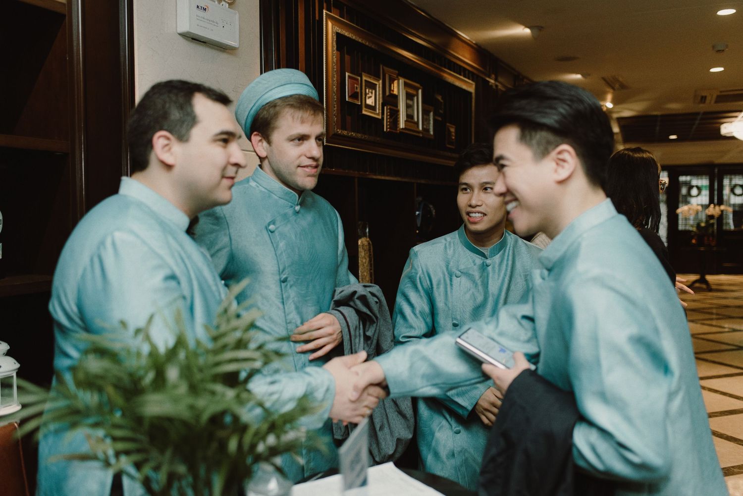 A group in matching light blue attire having an animated discussion in an indoor setting.