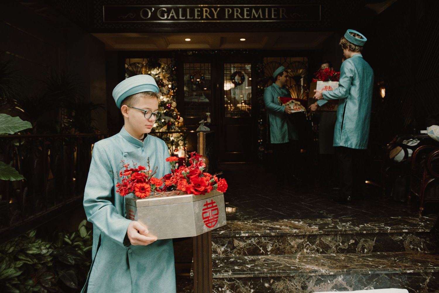 Art gallery entrance with formal gathering and red floral decorations.