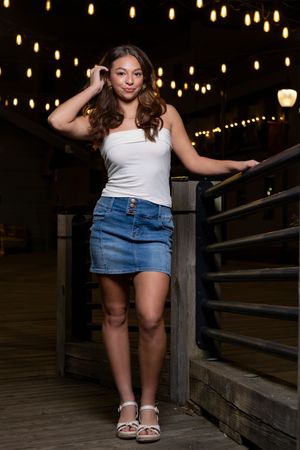 Standing on a wooden deck at night with string lights creating a magical bokeh backdrop.