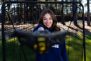 Through a black fence with blurred background, a playful portrait is captured in soft focus.