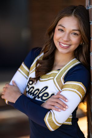 Close up portrait wearing navy and gold Eagles cheerleading uniform.