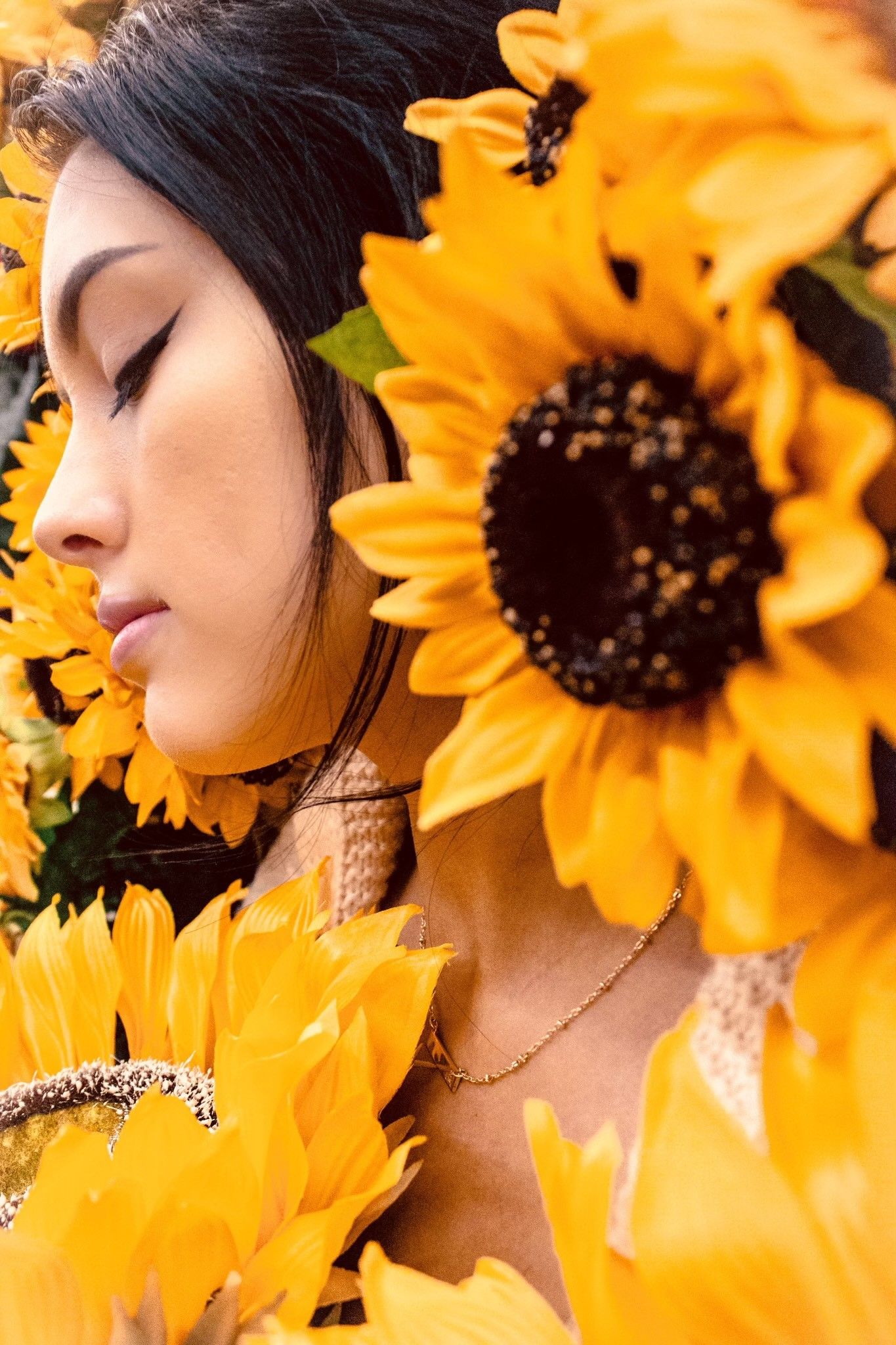 Artistic portrait surrounded by vibrant yellow sunflowers in a dreamy summer aesthetic.