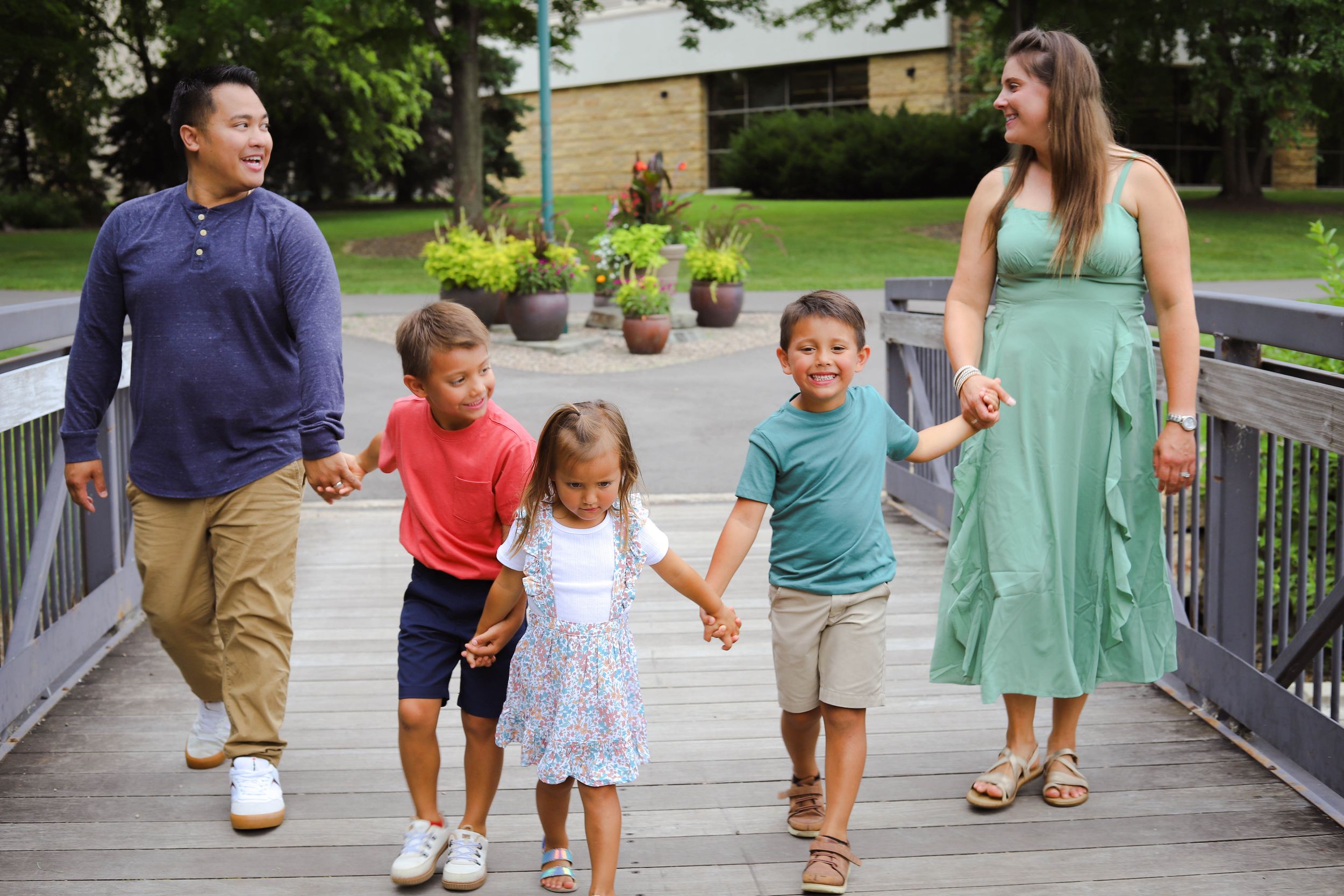 A group walking together and holding hands on a wooden boardwalk on a sunny summer day.