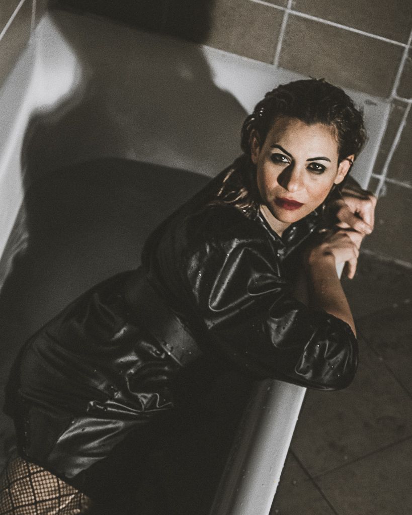 Moody fashion portraits against industrial backdrop with leather jacket and dramatic lighting.