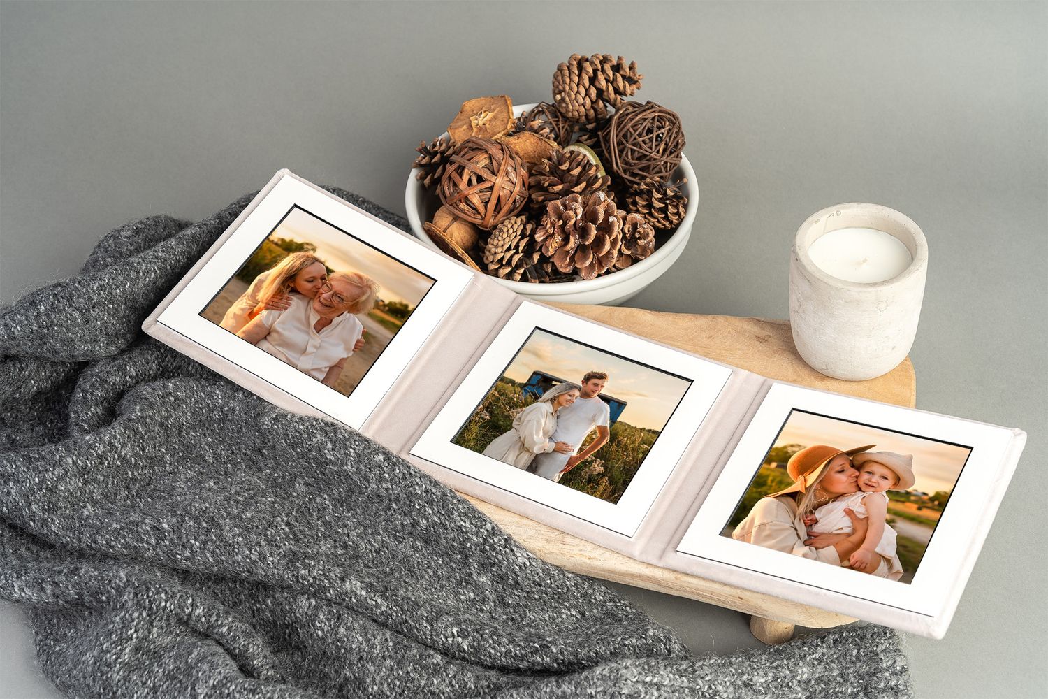 Collection of cozy photo album pages with photographs displayed on a gray wool blanket next to warm tones and textures.