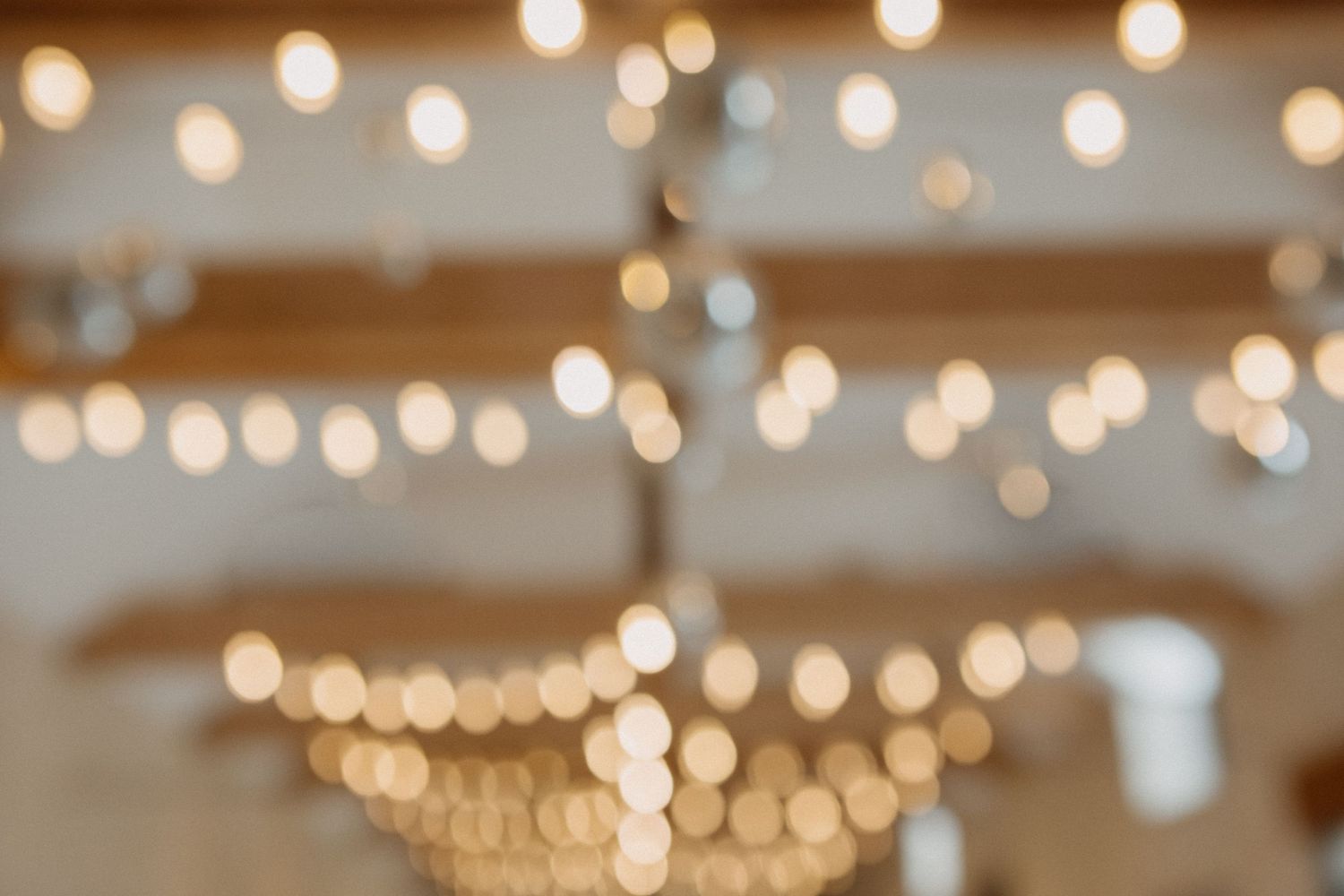 Warm bokeh string lights creating romantic ambiance in elegant wedding barn reception venue.