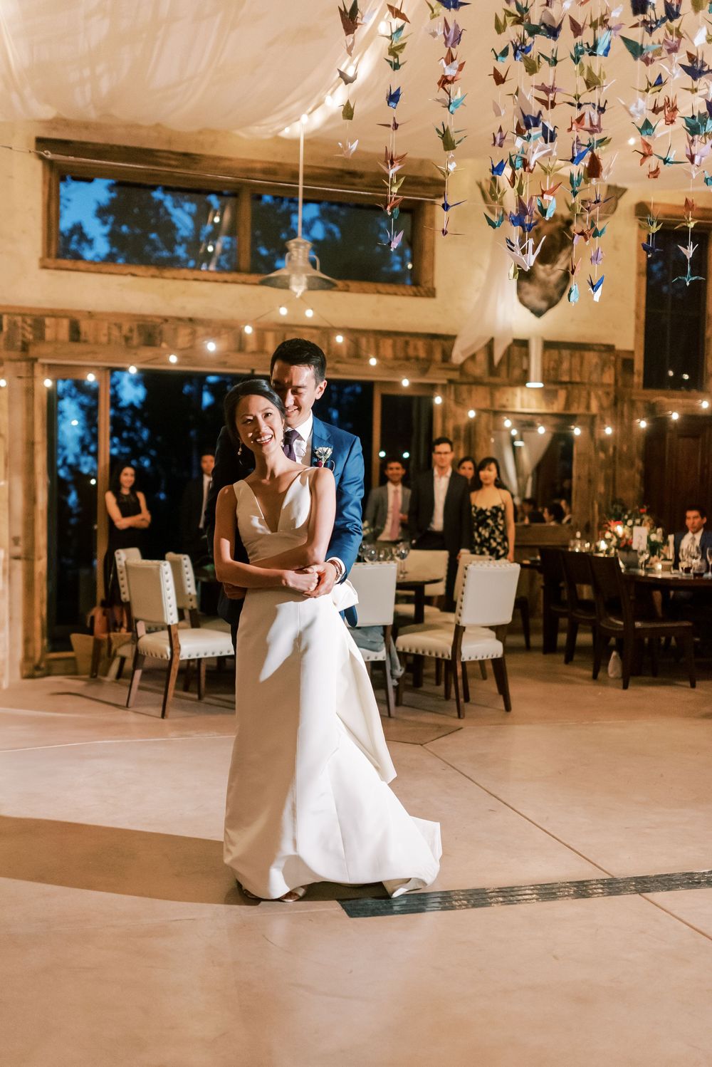 Couple dancing in a mountain wedding venue with twinkling lights and origami cranes overhead, photo by Fayetteville Wedding Photographer