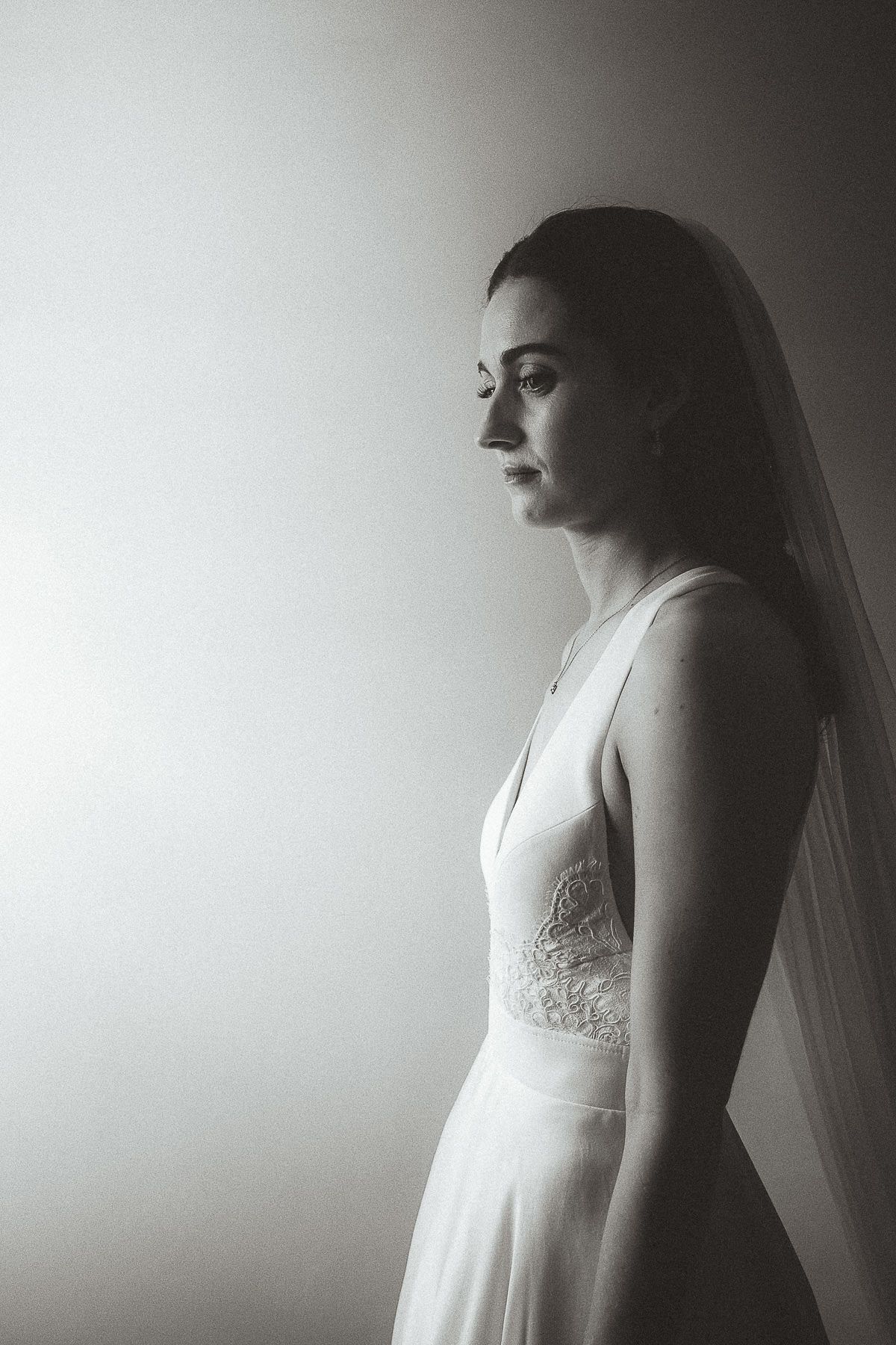 A series of black and white portraits showing a bride in a lace wedding dress and veil in various side profiles.