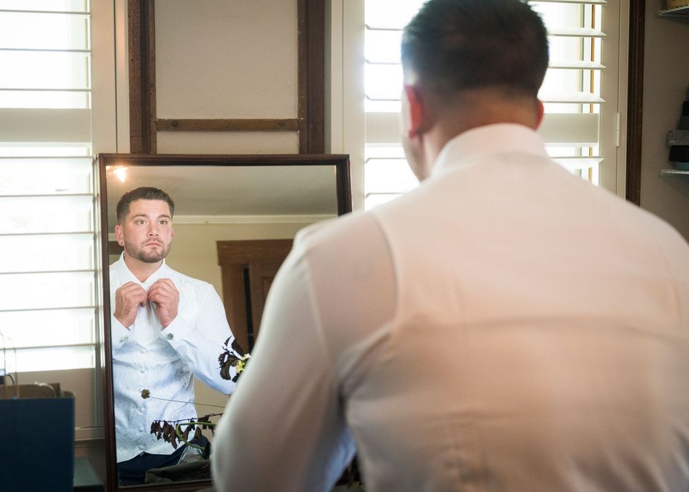 Wedding preparation scene in a bright room with white shirts and formal attire.