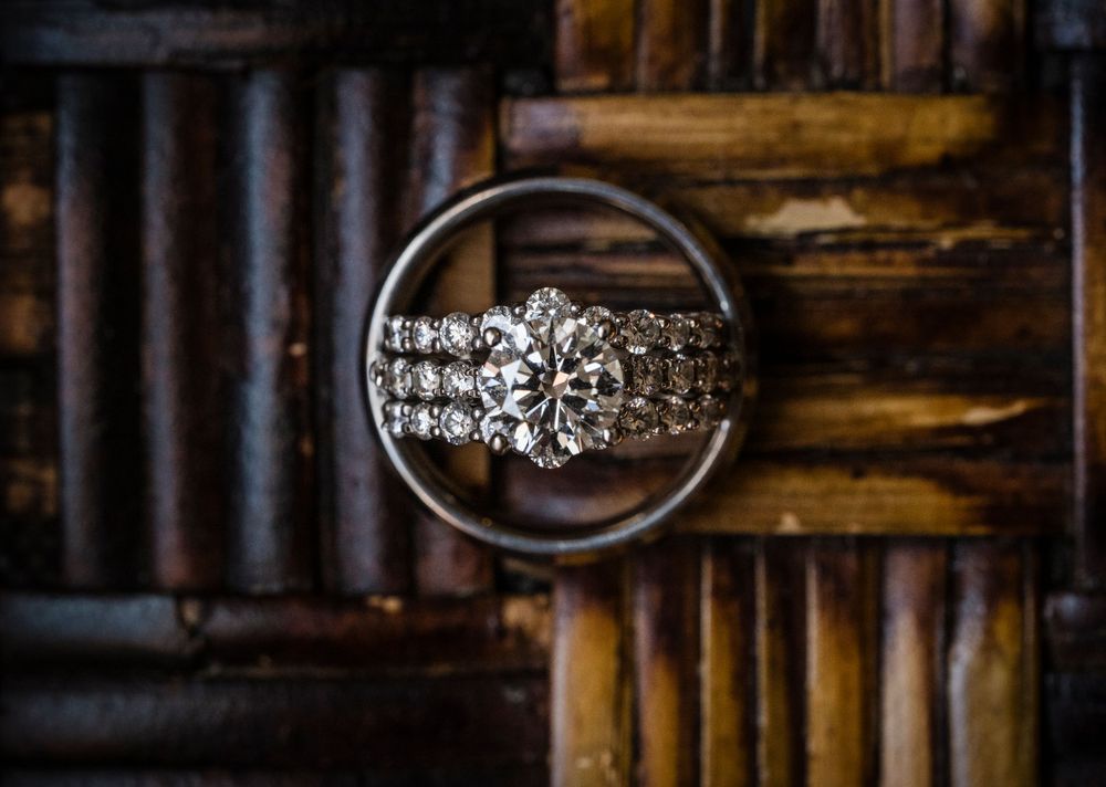 Wedding rings and jewelry laid out on a textured wooden surface in dramatic lighting.