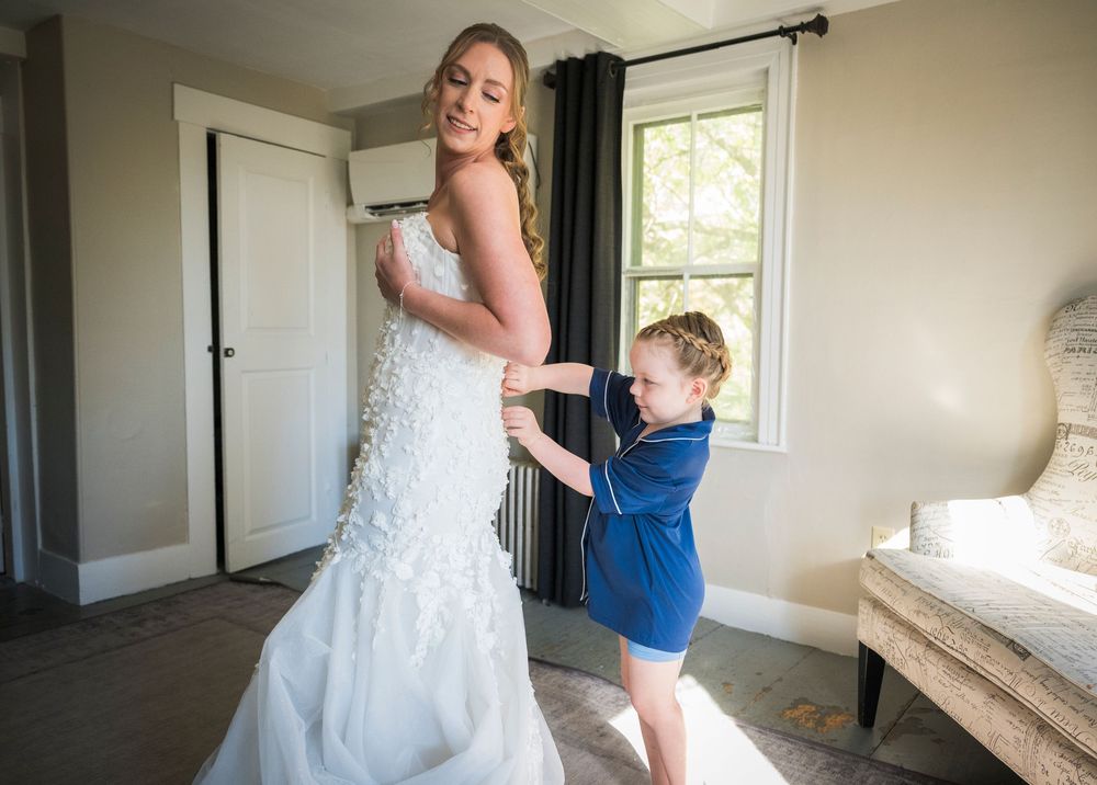 Emotional wedding day preparation moments in sunlit room with white dress and blue attire.
