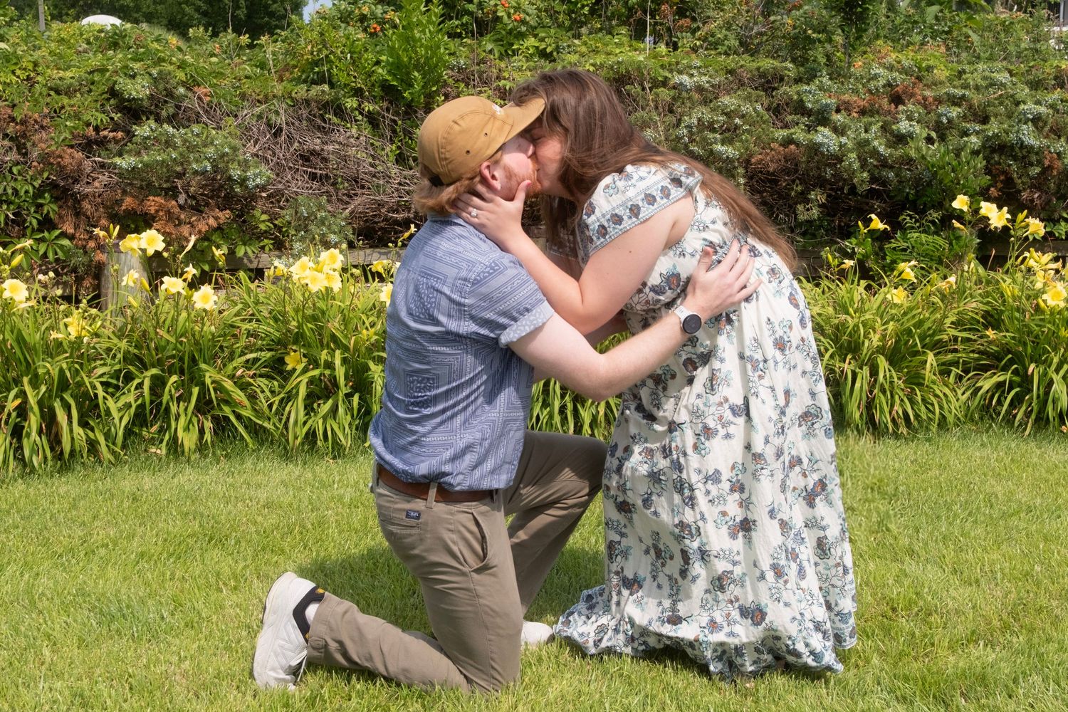 A romantic proposal moment captured in a garden with blooming flowers.