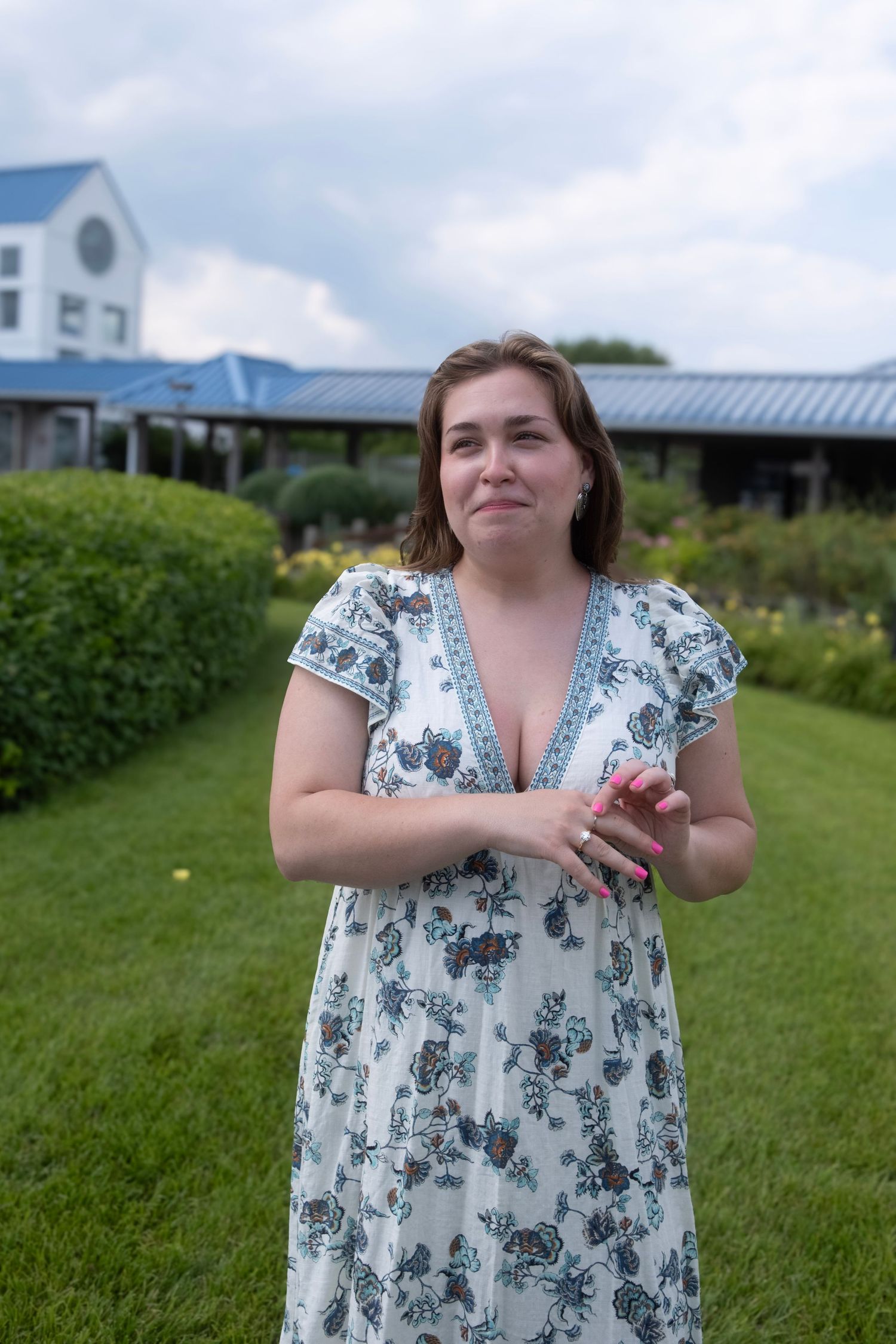 A joyful moment captured in a garden setting with flowering plants and buildings in background.