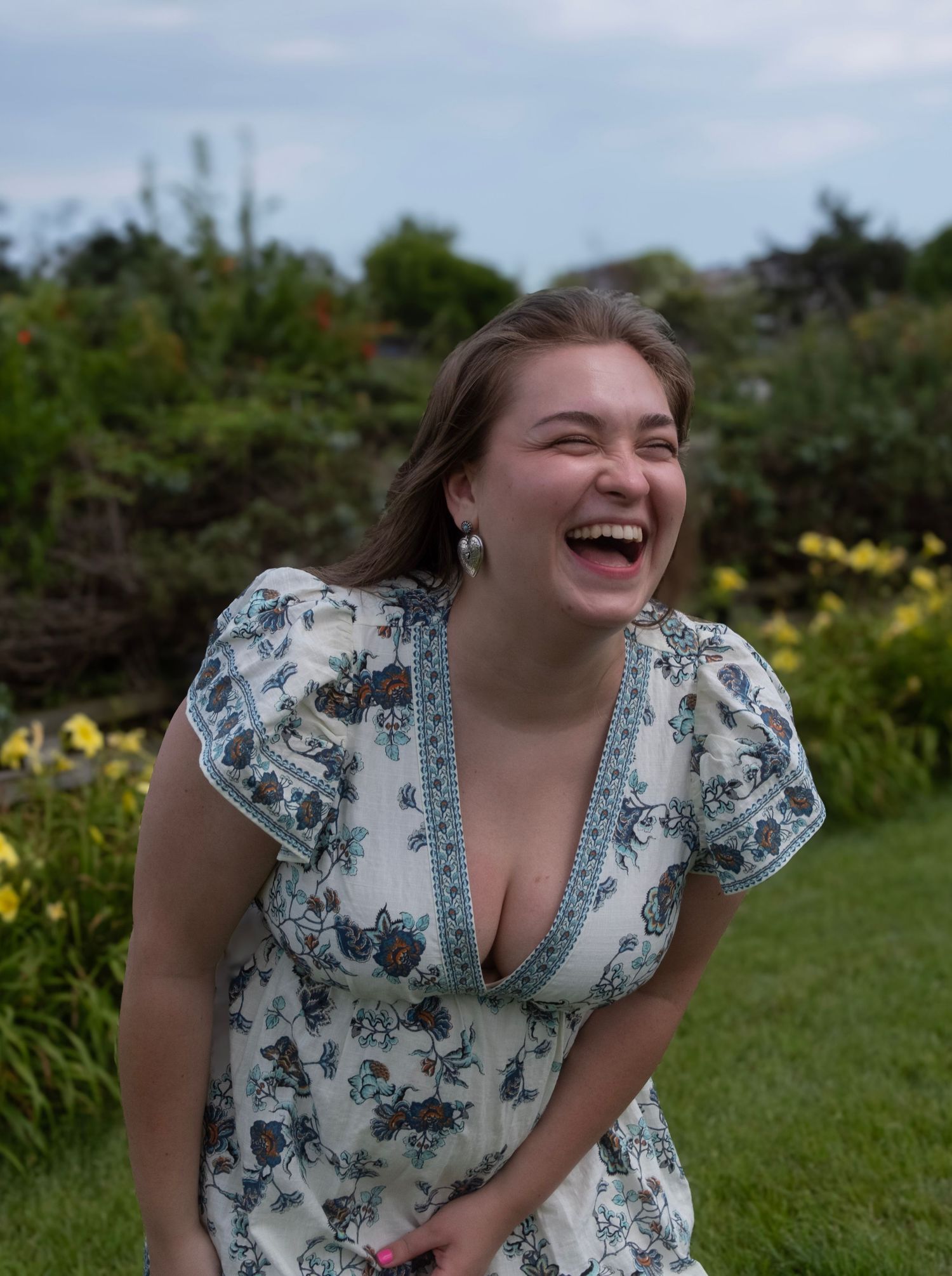 Someone expressing pure joy and laughter in a sunny garden setting.