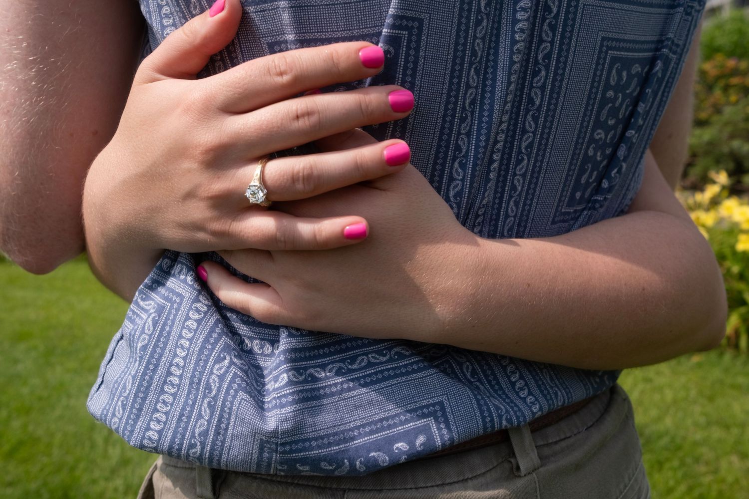 Close-up of hands showing off a new engagement ring with pink nail polish.