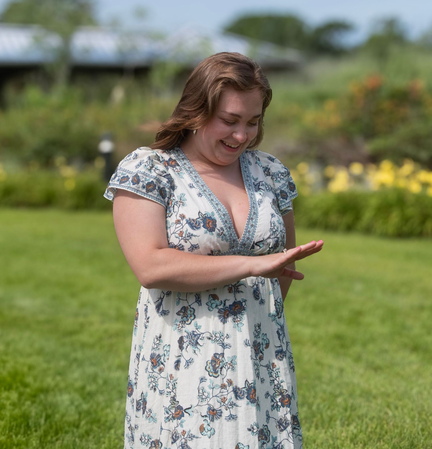 A candid reaction shot in a garden setting with yellow flowers and greenery.
