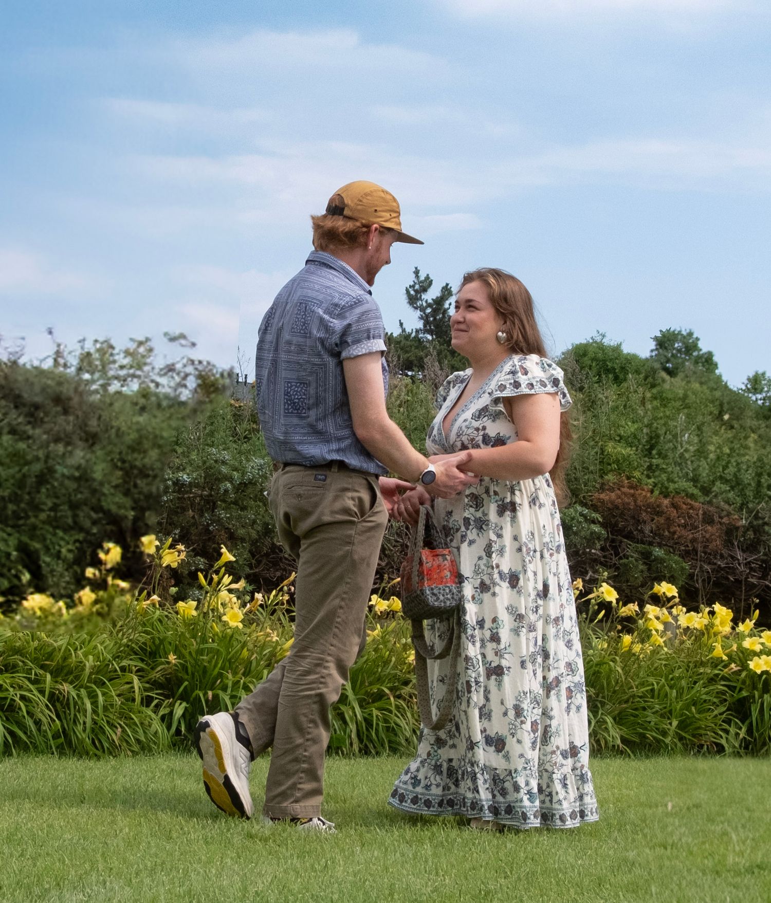 A marriage proposal scene taking place in a sunny garden with yellow daylilies in the background.