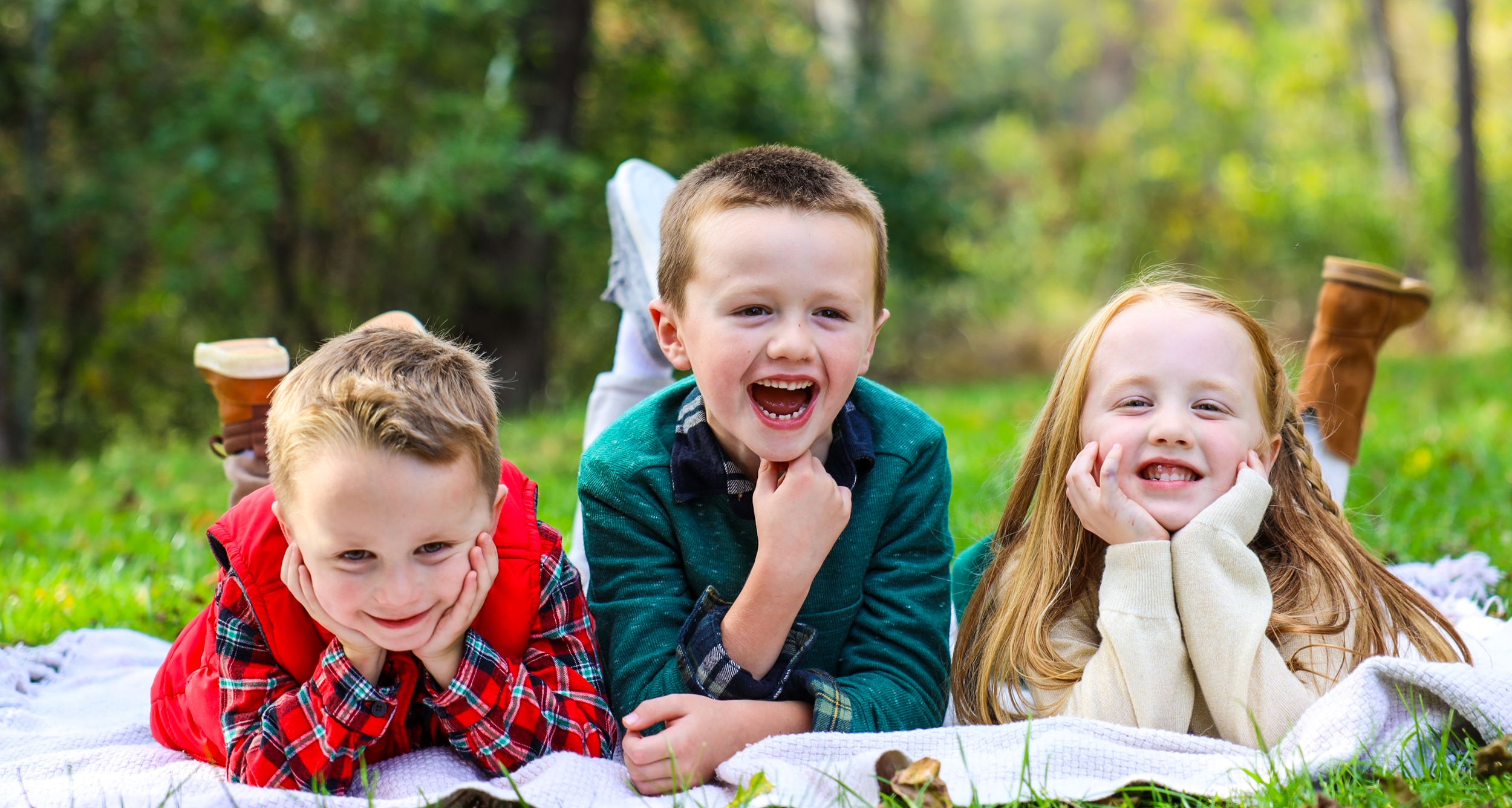 Group of children laughing together outdoors in casual fall attire.