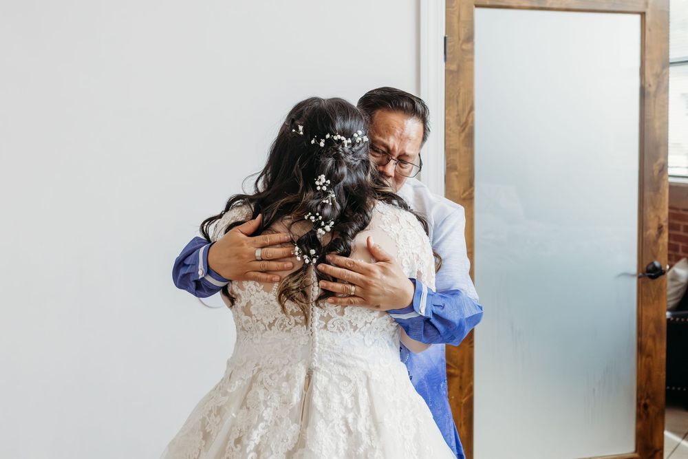 A loving embrace between two people at a wedding, with the bride wearing a beautiful white lace dress.