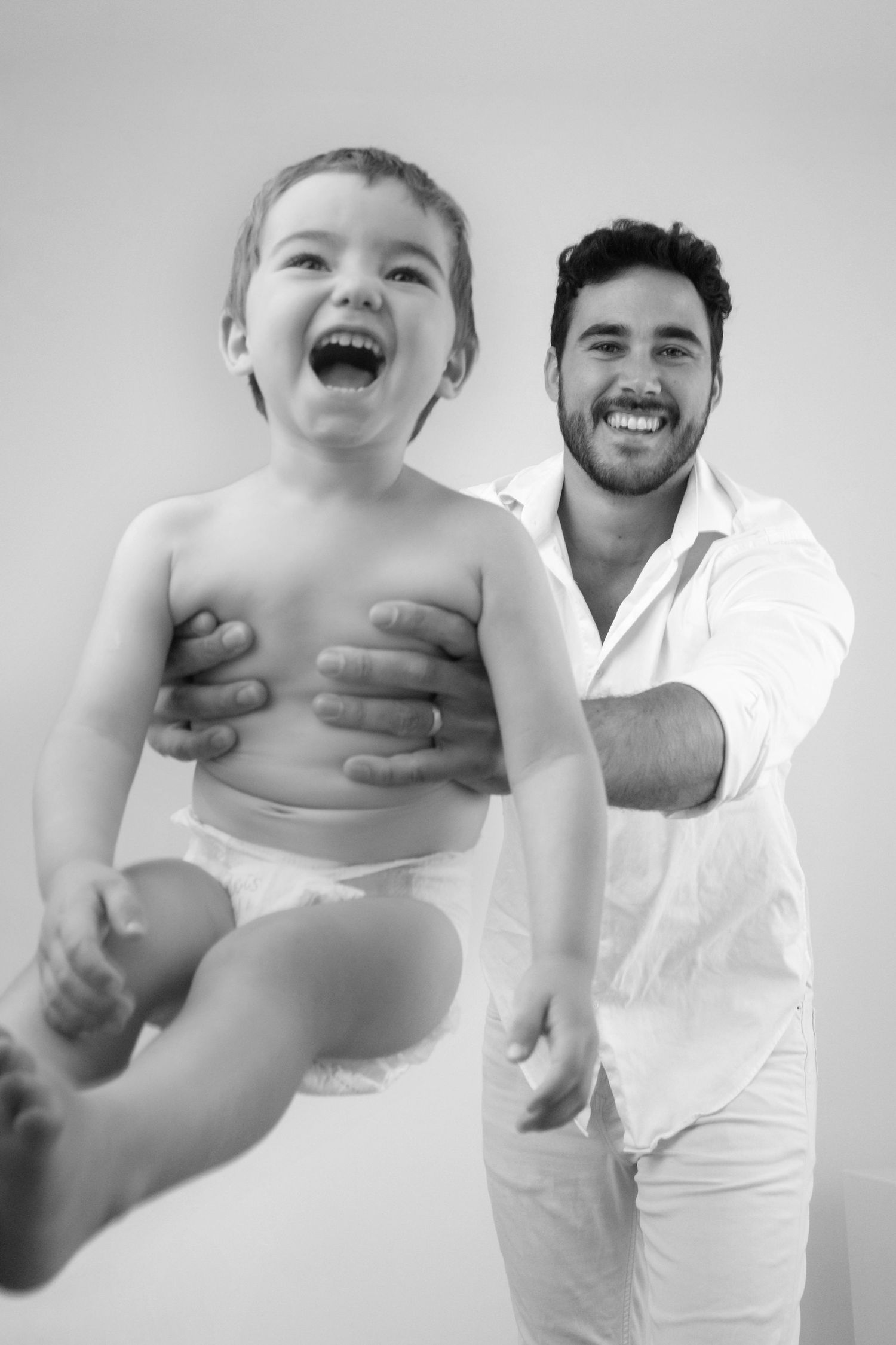 Fotografía en blanco y negro de un padre jugando con su hijo pequeño en un momento de alegría y felicidad