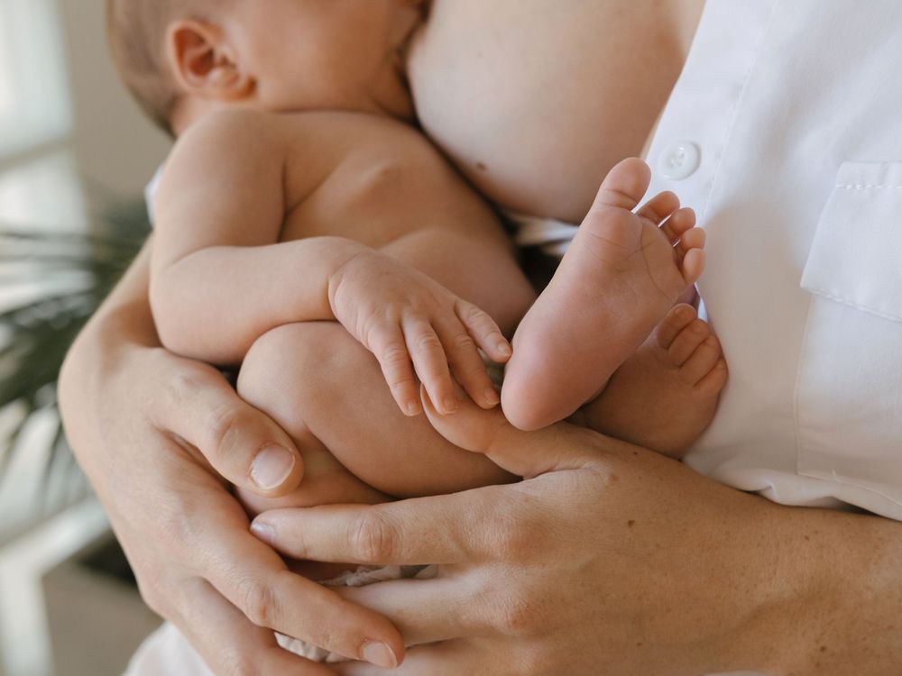 Fotografía de detalle de los pies de un bebé recién nacido en brazos de su madre