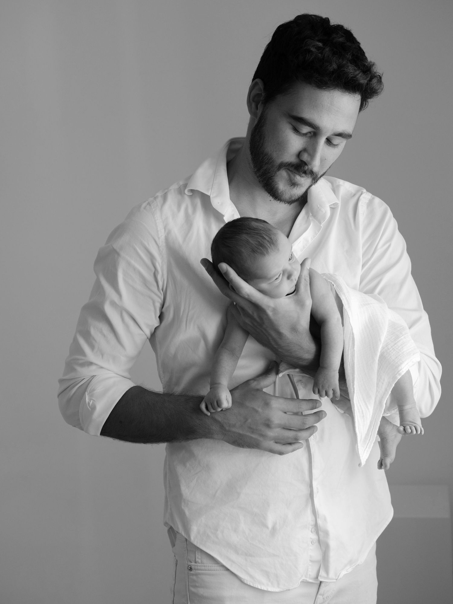 Tierno retrato en blanco y negro de un padre sosteniendo a su bebé recién nacido
