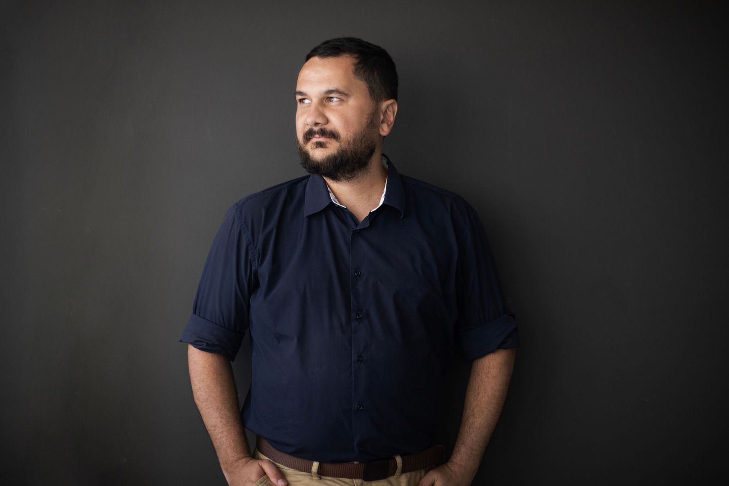 A person in a navy blue shirt appears at different angles in a series of dark, moody portrait photographs.