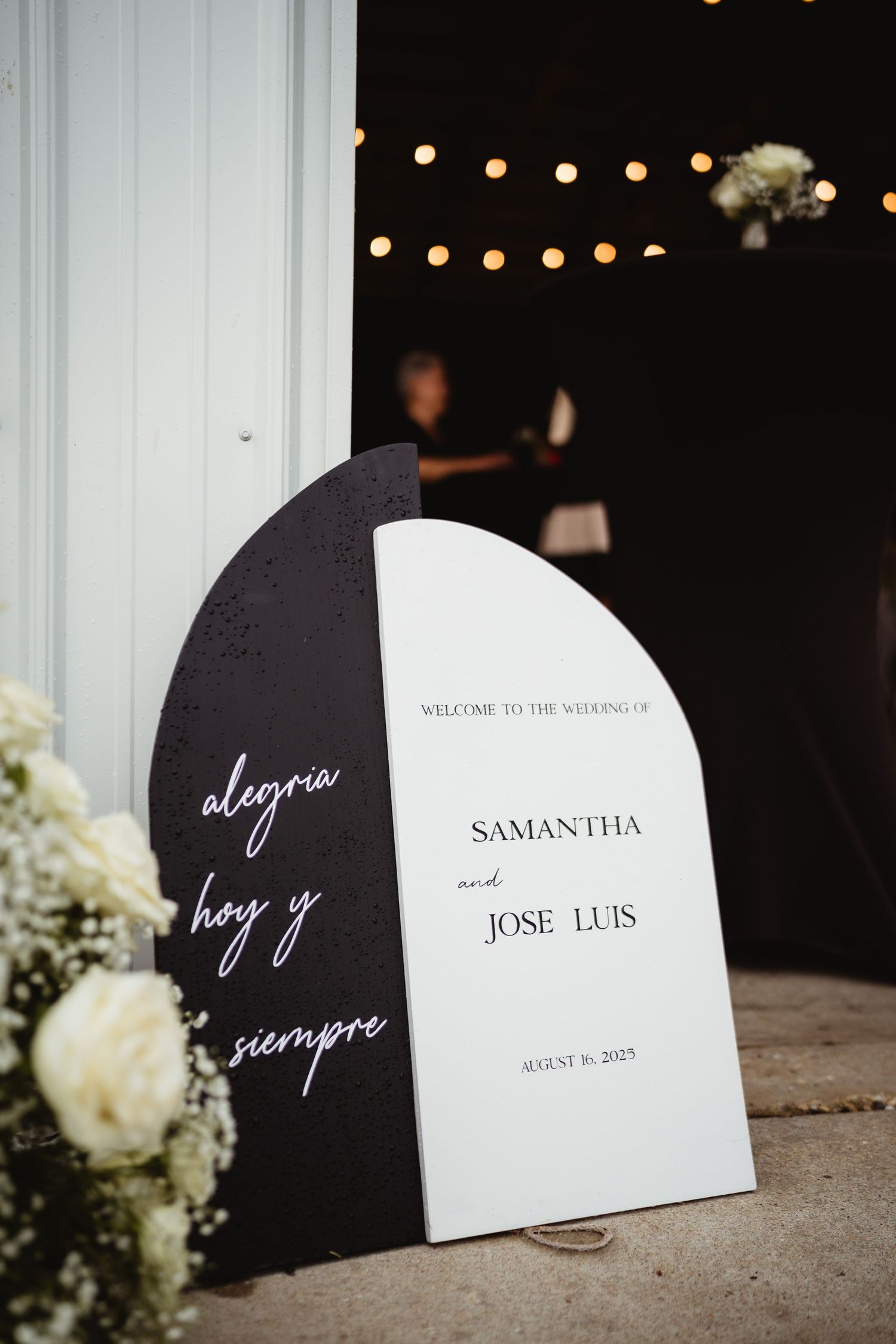 Modern curved black and white place cards with elegant calligraphy names displayed at an evening wedding reception.