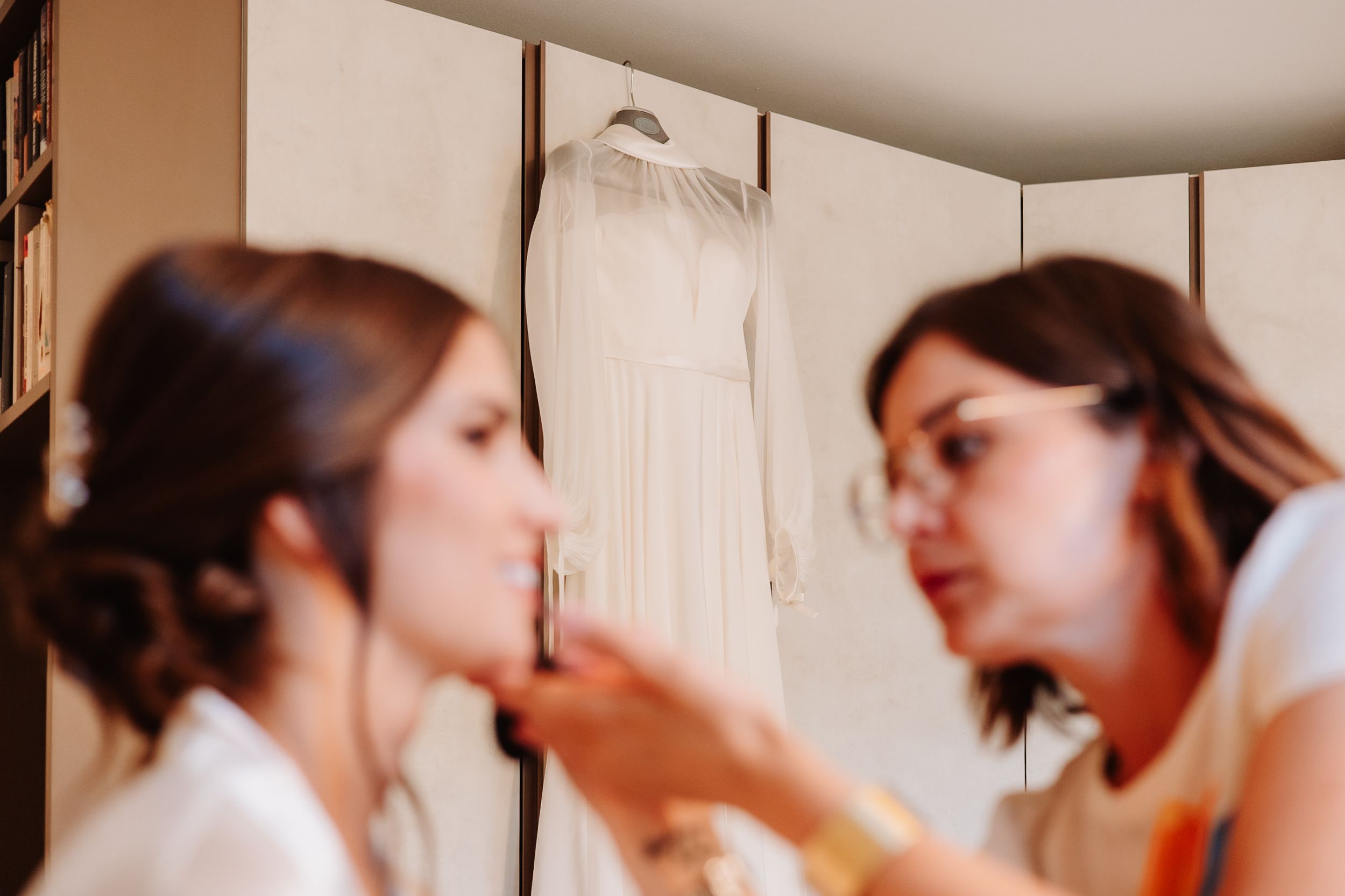 Wedding day preparations showing hairstyling session in a softly lit room.