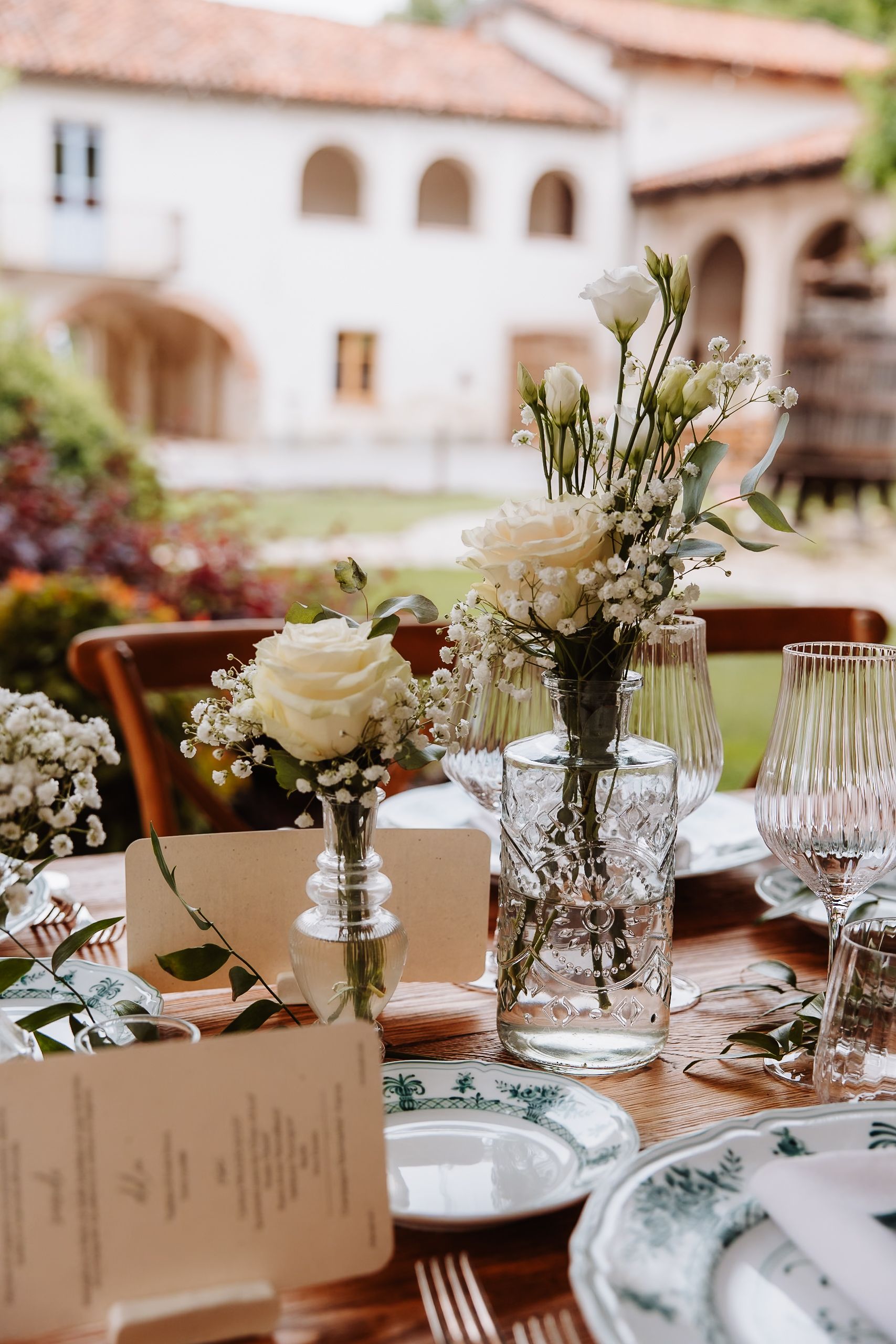Elegant wedding reception table setting with white roses, baby's breath flowers, and printed menu cards.