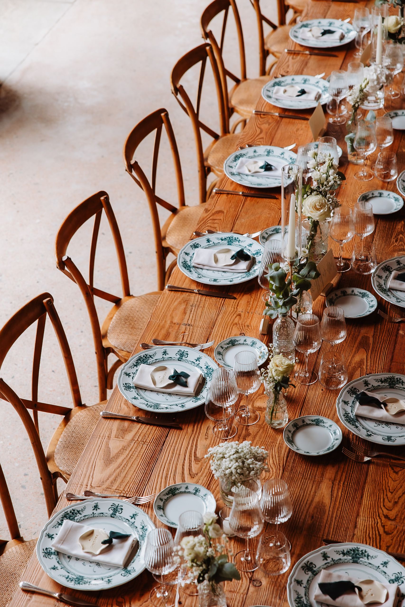 Elegant table setting with wooden chairs and decorative plates arranged along a rustic wooden dining table.