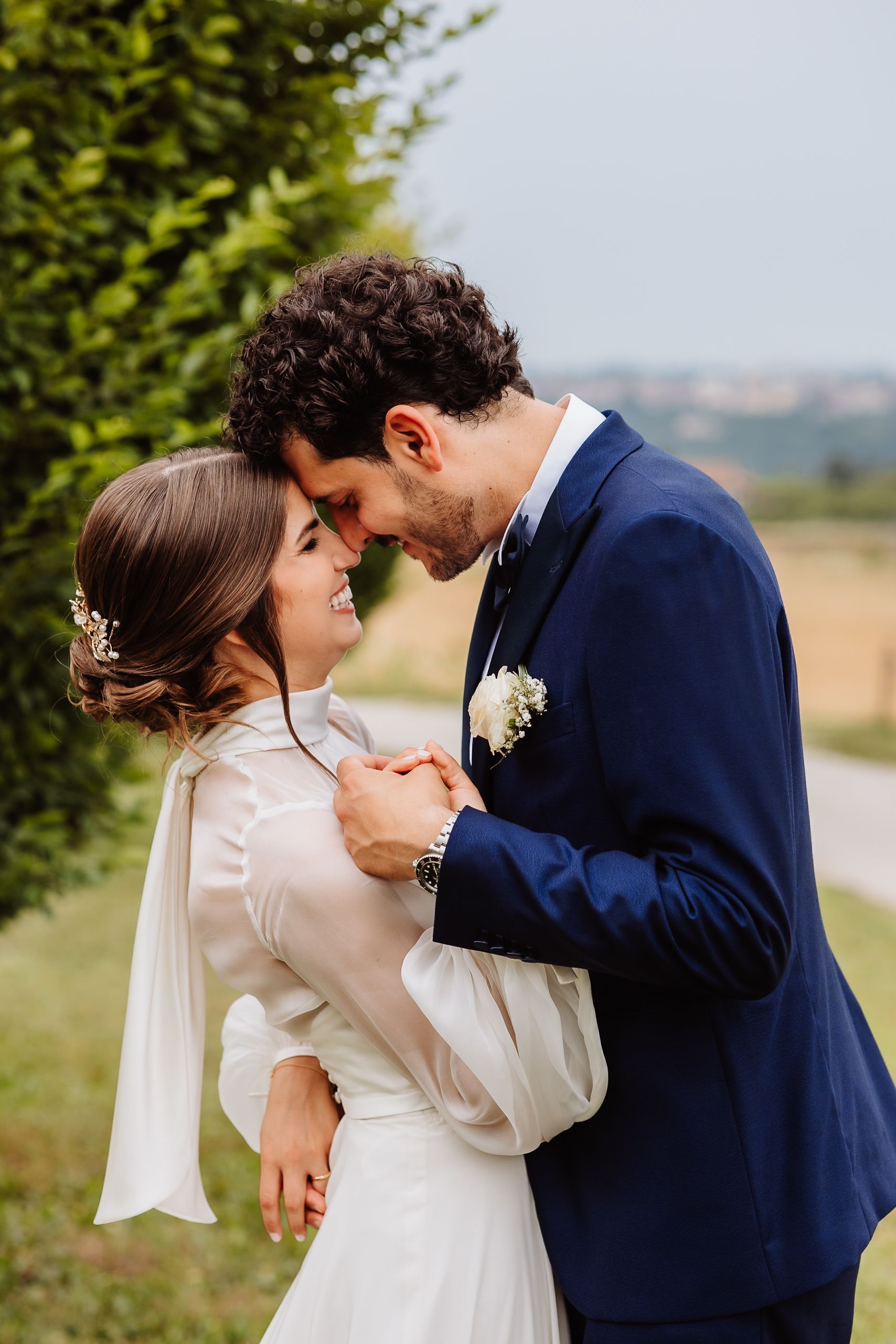A romantic moment between a couple outdoors on their wedding day as they share an intimate gesture in formal attire.