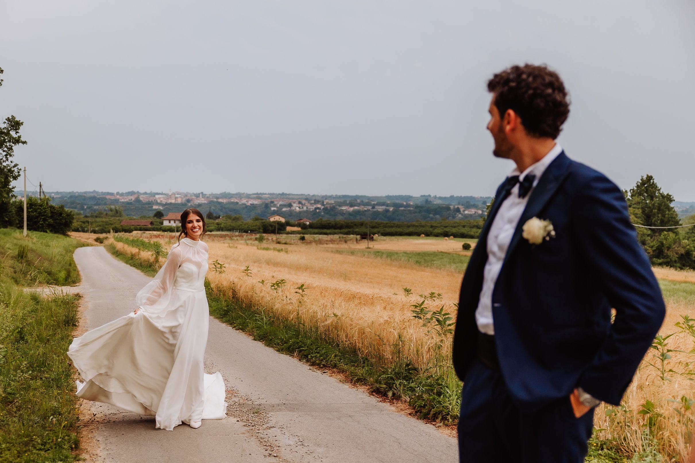 Wedding couple poses on a country path with rolling fields and farmland in the scenic rural background.