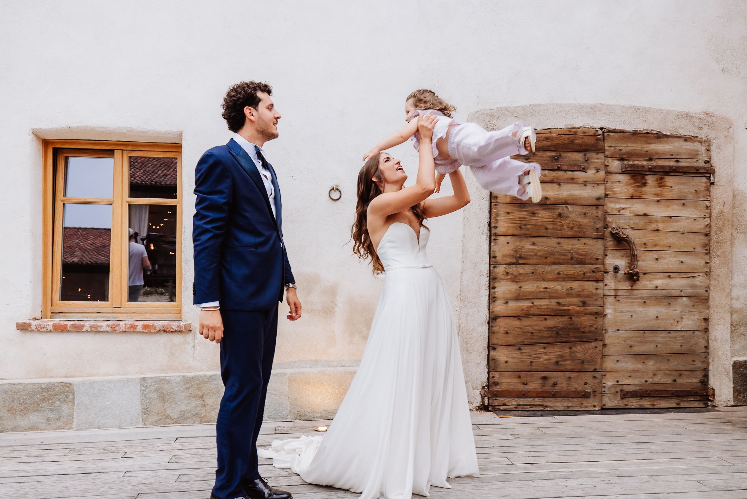 A romantic moment at a rustic barn venue shows a dancing couple in wedding attire gliding across the wooden floor.