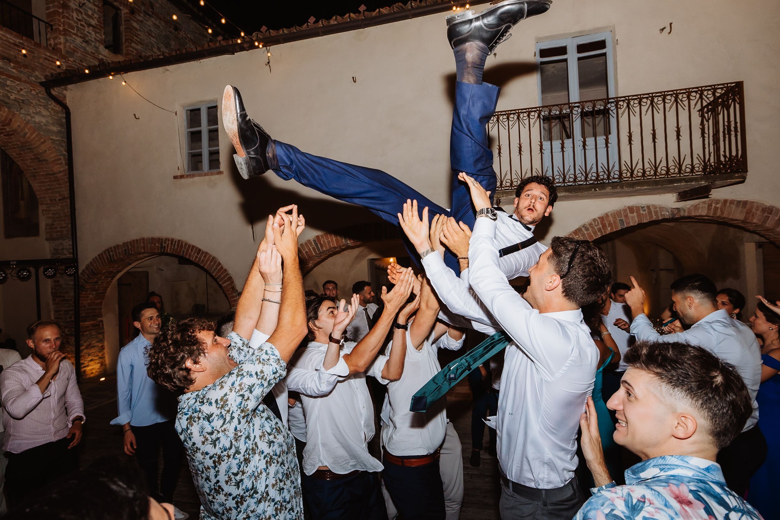 A group of people dancing energetically in a dimly lit room while celebrating at a party event.