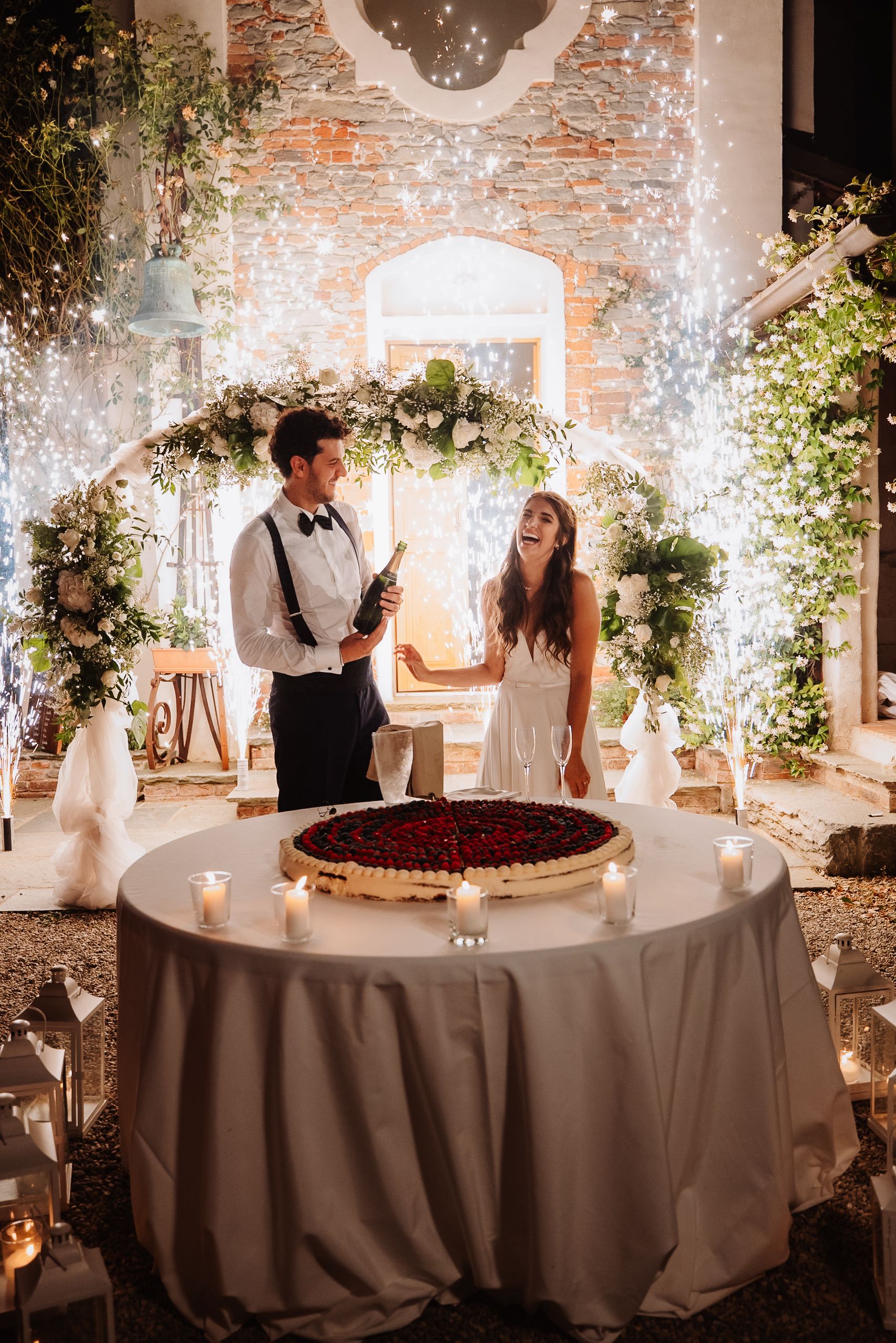 A wedding reception cake cutting series showing couple at a round table with exposed brick wall and elegant floral decor.
