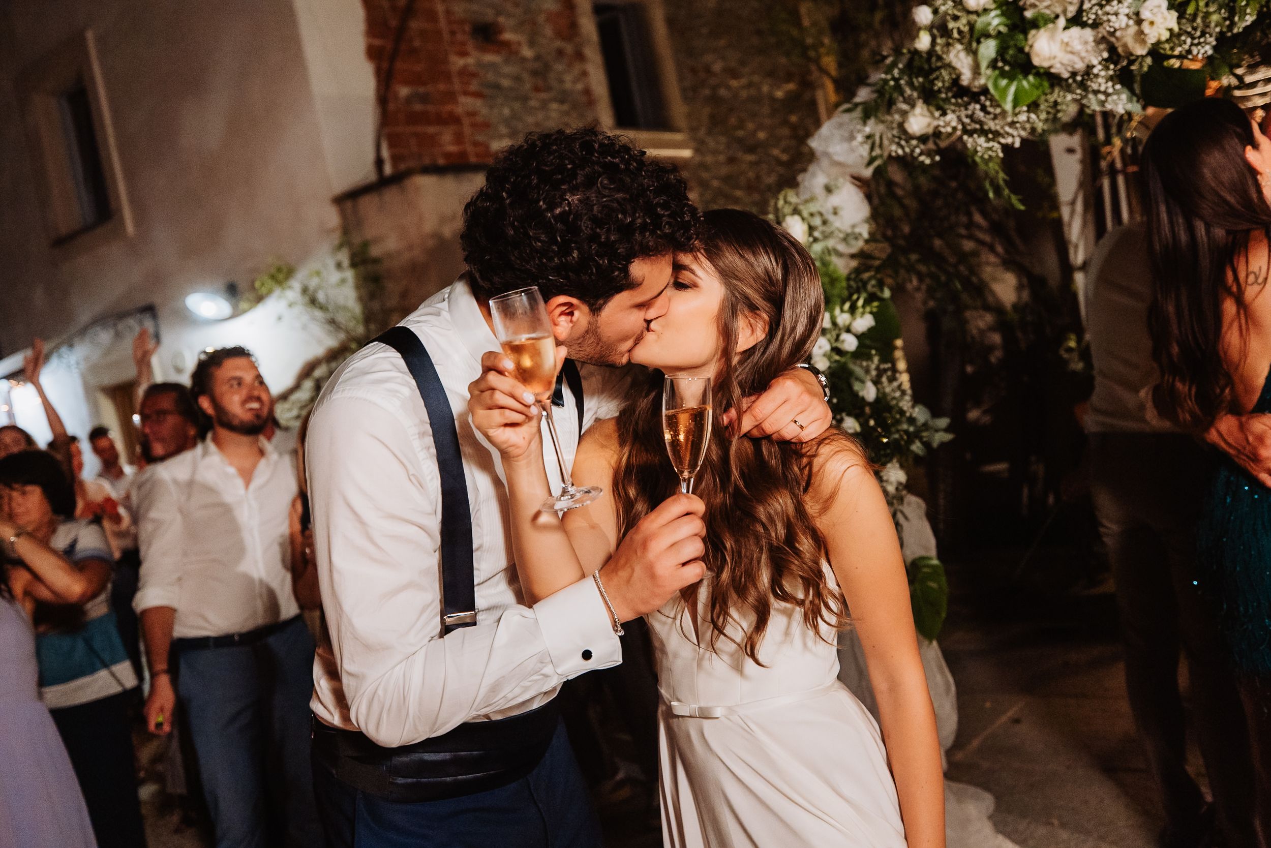 A couple shares an intimate dancing moment at a wedding reception as guests watch in the background.