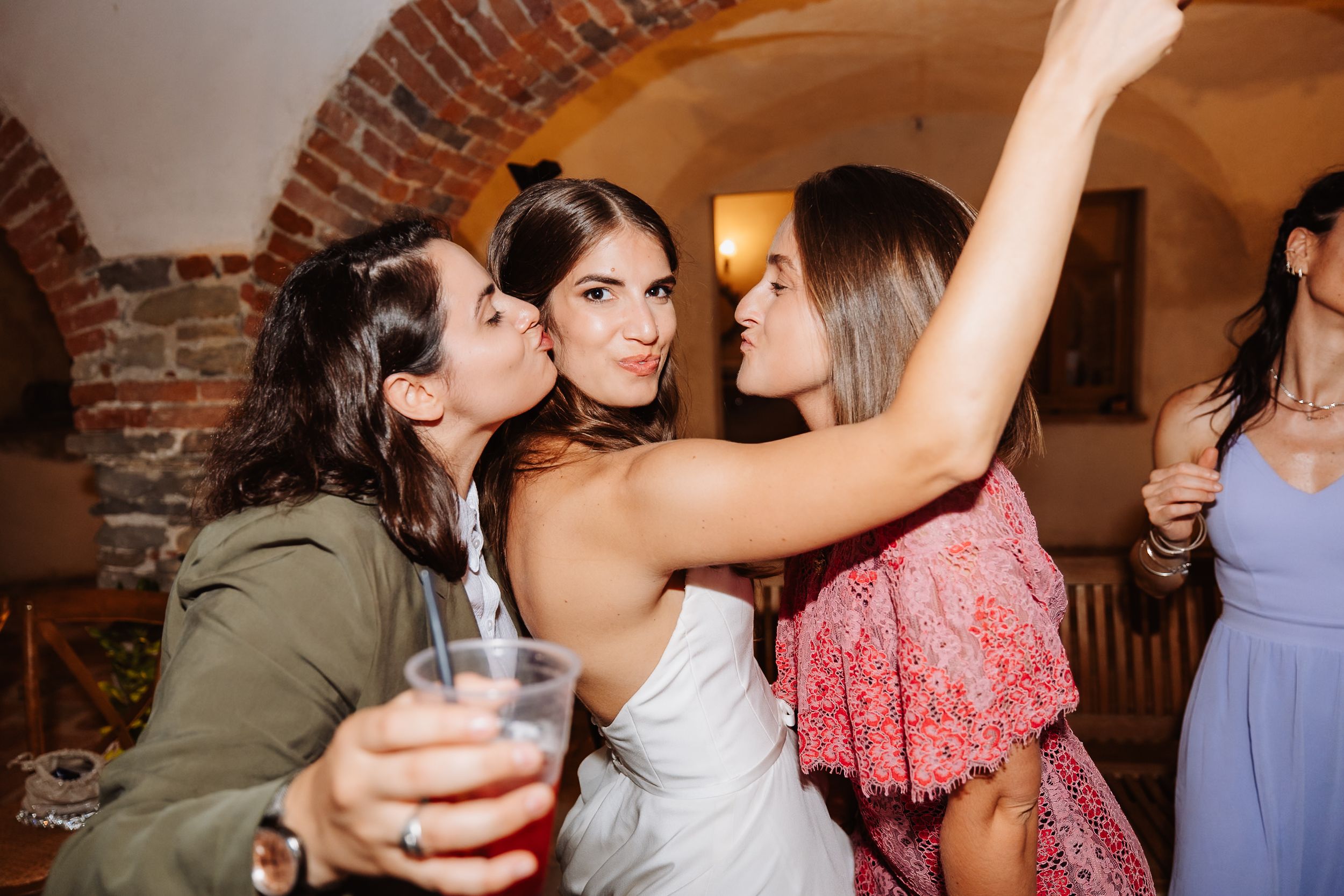 Party guests dancing and having fun together with cocktails in a room with brick archways.