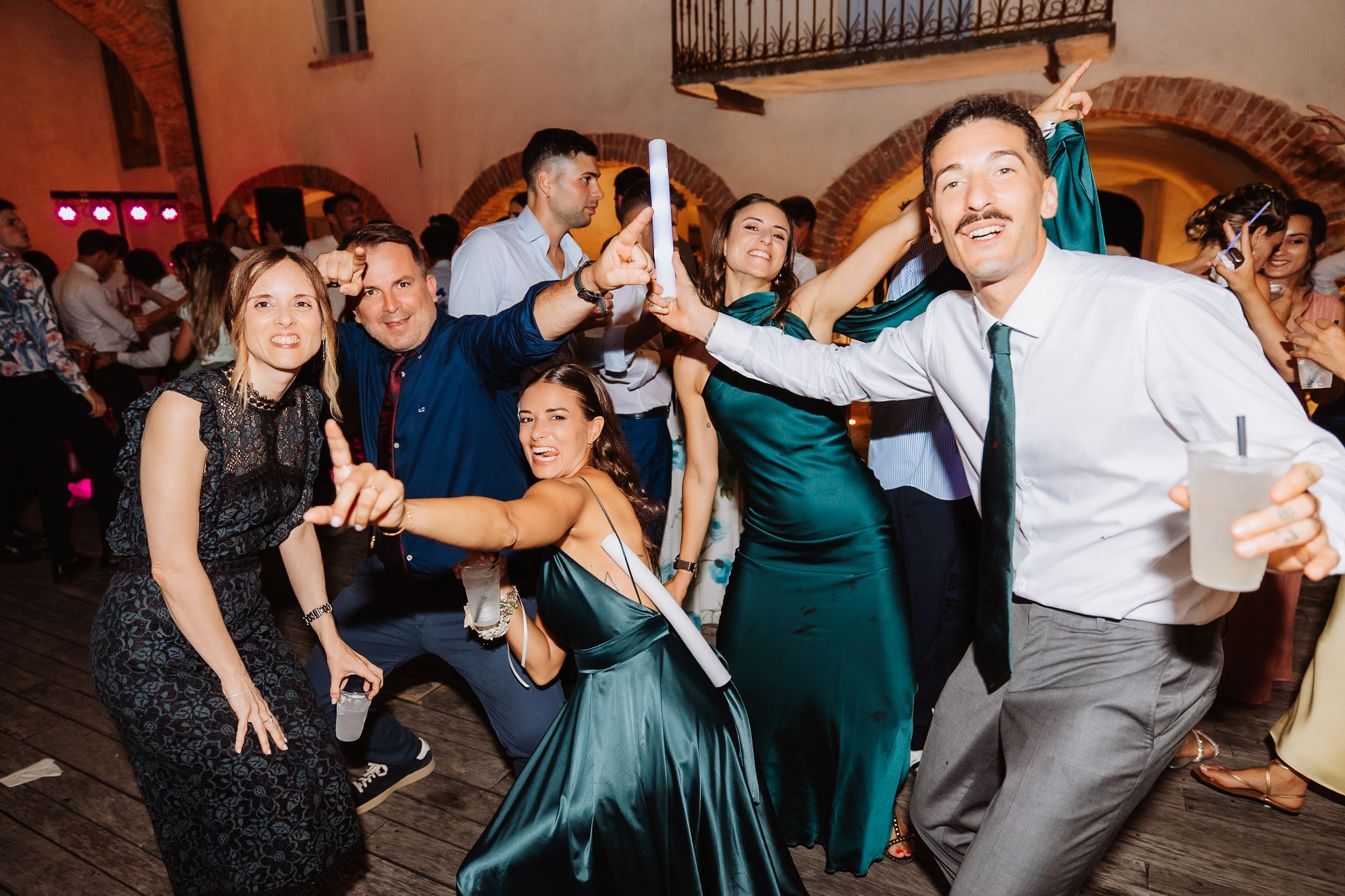 People dancing together in formal attire at a wedding reception inside an elegant ballroom.