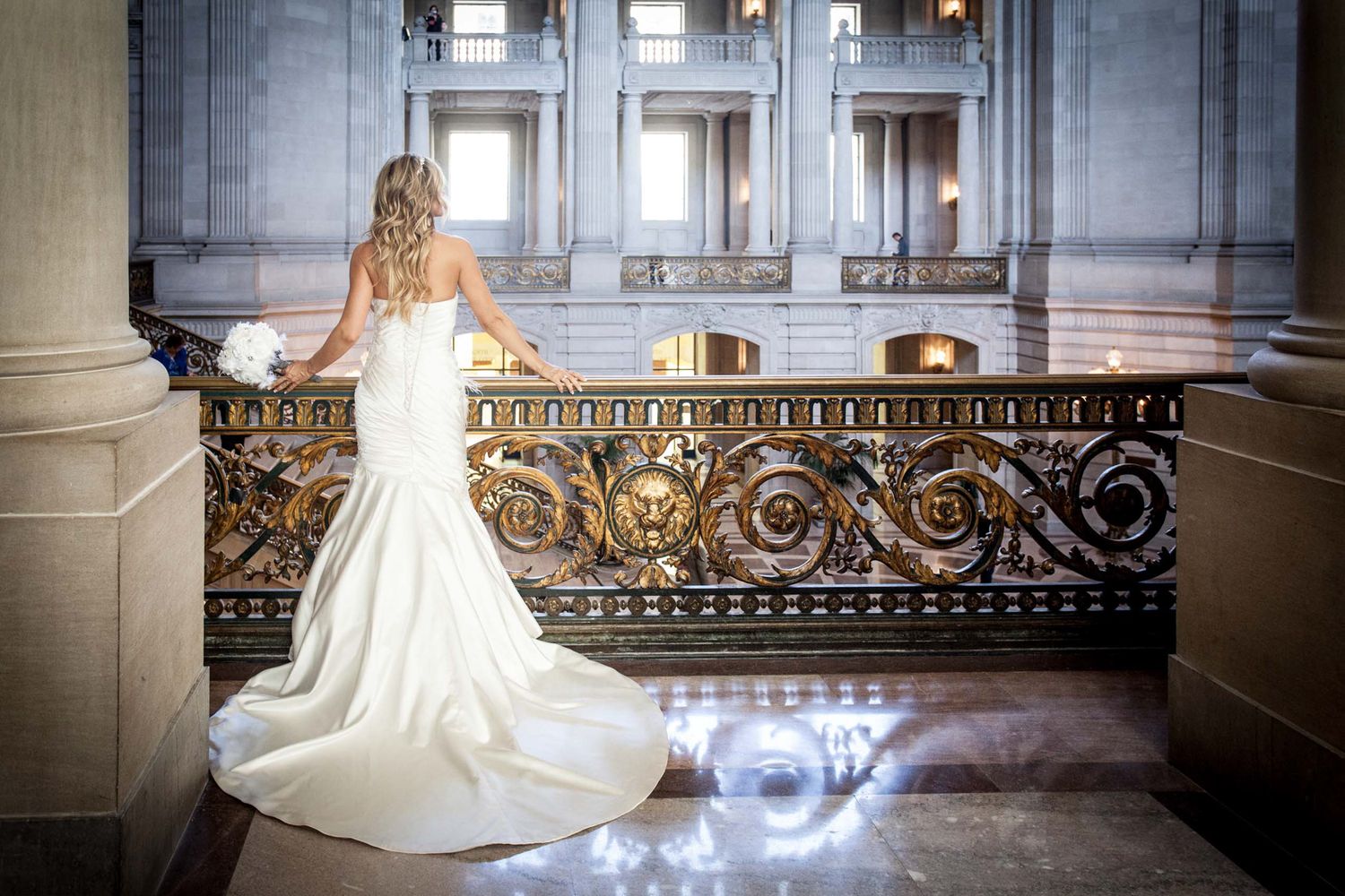 Dramatic bridal gown with flowing train photographed in an ornate classical interior.