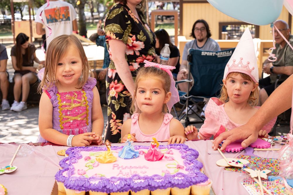 Children gather around colorful craft tables at a birthday party doing creative activities with art supplies and decorations.
