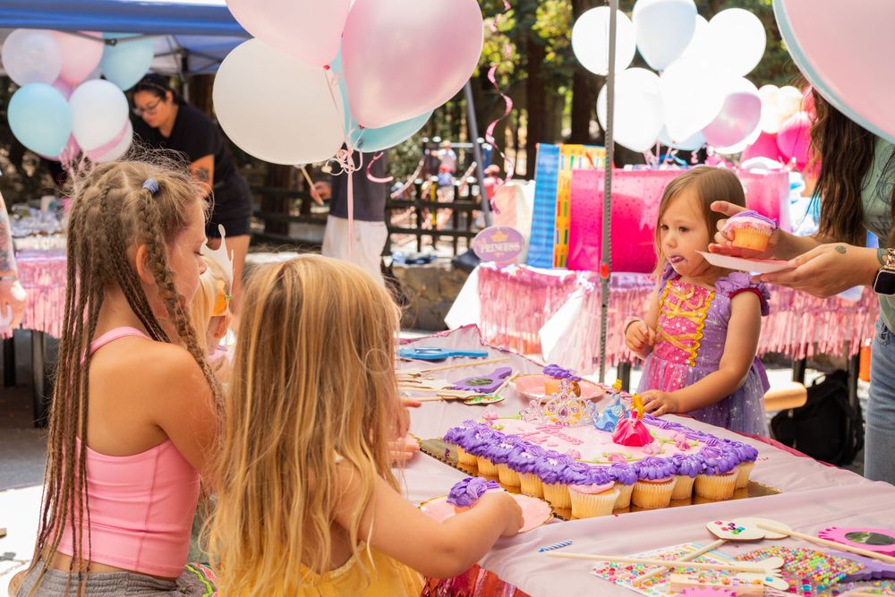 Children enjoying a pink-themed birthday party with balloons and decorative elements at an outdoor celebration.
