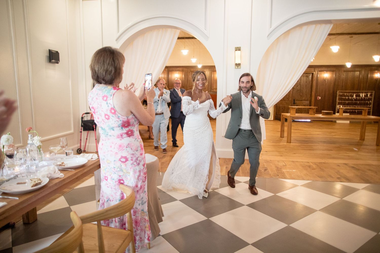 Wedding couple holds hands while laughing and dancing during their reception celebration.