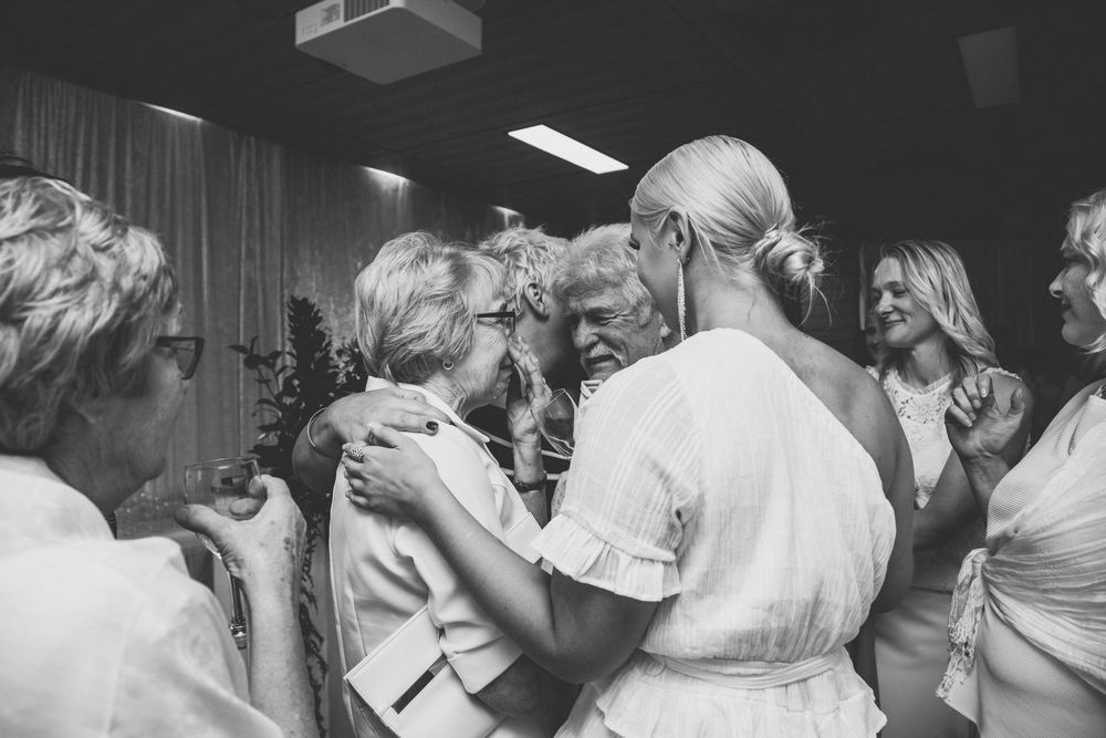Black and white photo showing people gathered in conversation at what appears to be a social event or gathering.