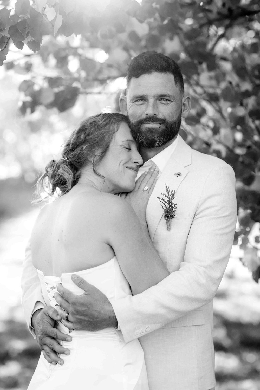 Black and white intimate wedding portrait of a couple embracing outdoors in natural lighting.