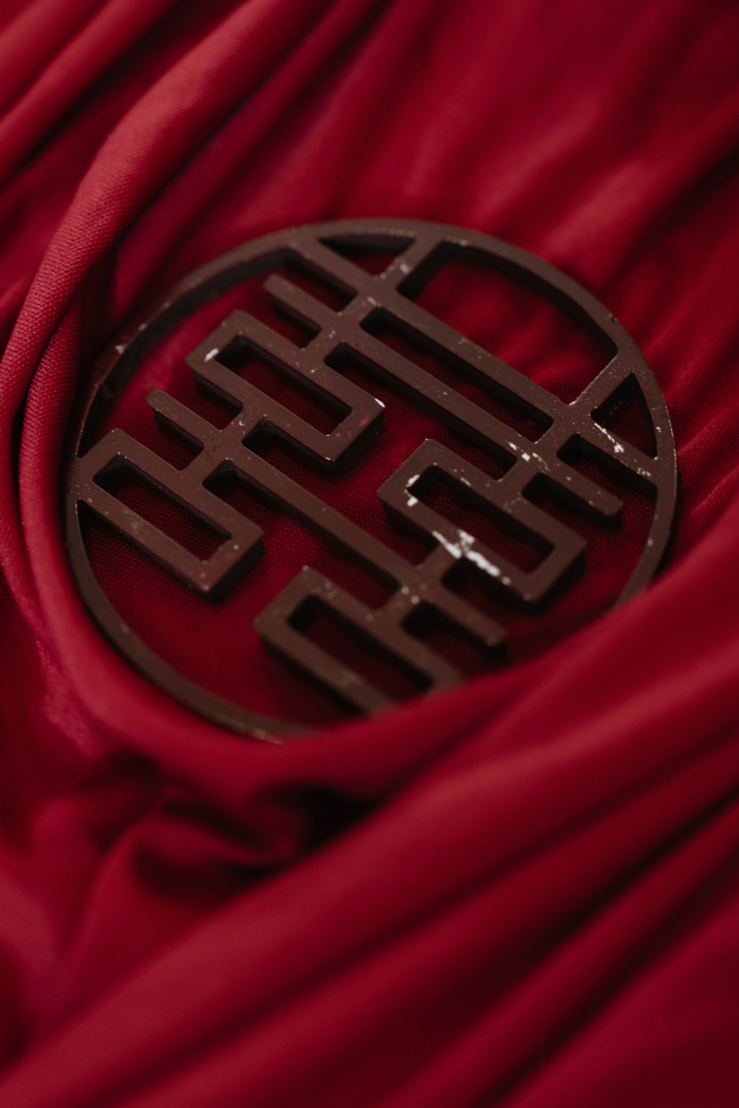 Close-up of ornate double happiness symbol on red fabric for traditional Chinese wedding decor.